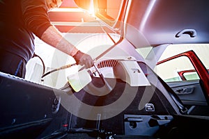 A car service worker cleans interiror with a special foam generator