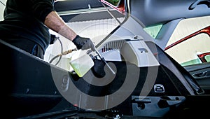 A car service worker cleans interiror with a special foam generator