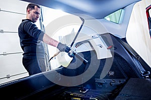 A car service worker cleans interiror with a special foam generator