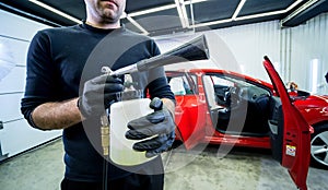 A car service worker cleans interiror with a special foam generator