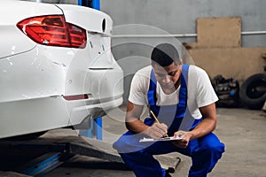 A car service worker with a clipboard inspects car