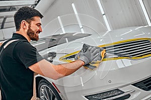 Car service worker polishing car with microfiber cloth