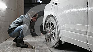 Car service: The worker washes car rims with a soft brush with shampoo