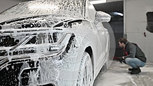 Car service: The worker washes car rims with a soft brush with shampoo