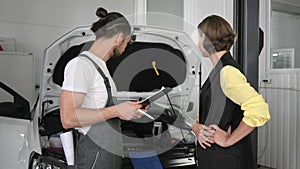 Car service, a young mechanic stands next automobile