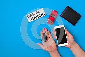 Car sharing app concept. Toy car, auto drive license, human hand with smartphone and car key, text sign