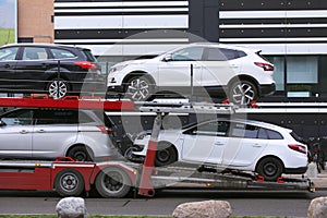 Car shipping auto transport vehicle with cars loaded in front of office buildings