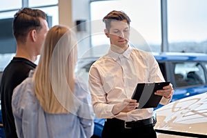 Car showroom. Rear view on couple choosing new car auto before buying purchasing automobile