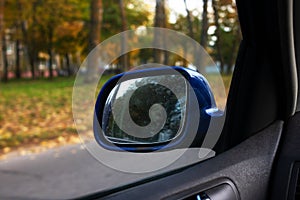 Car side mirror on the background of the autumn road