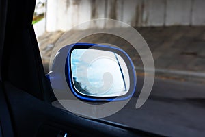 Car side mirror on the background of the autumn road