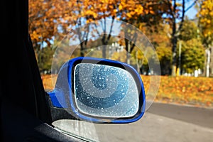 Car side mirror on the background of the autumn road