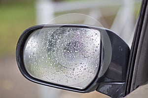 Car side mirror with water drops close up