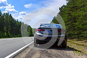 A car on side of a suburban asphalt highway in wild forest at car trip