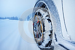 Car with snow chains for tire on snowcapped road