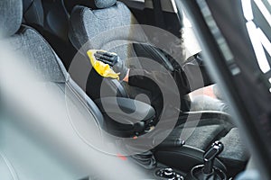 car specialist with black gloves cleaning the front seat with a cloth, car interior detailing