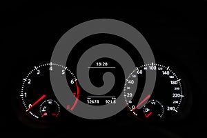 Car speedometer dashboard lit up in the dark