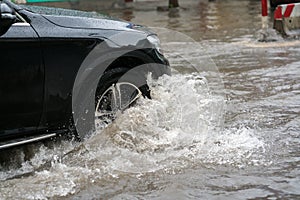 Car splashes through a large puddle on a flooded street