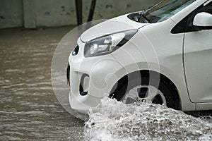 Car splashes through a large puddle on a flooded street