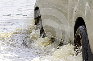 Car splashes through a large puddle on a flooded street