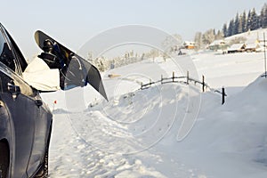 Women,s legs in snowboard from the car near beauty view of mountains and christmas trees in winter