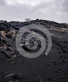 Car standing on a hill of black volcanic sand