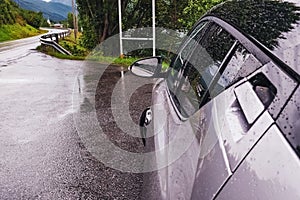 Car standing on the roadside on small country road on rainy day. Automobile travelling, road trip