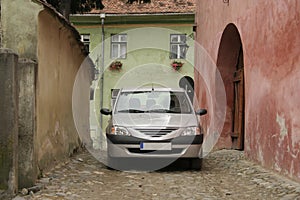 Car standing on the street in Sighisoara, Romania. Details of Romanian architecture, walls and gates. Classic stone street.