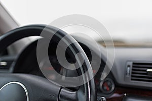 Car steering wheel dashboard on a blurry landscape.From above picture