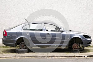 Car with stolen wheels for repair at garage lifted jacked up on bricks