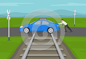 Car stopped on the tracks. Terrified businessman or manager pushing his blue sedan car stuck on railroad tracks.