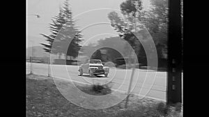 Car stopping by broken down police car on road, 1950s