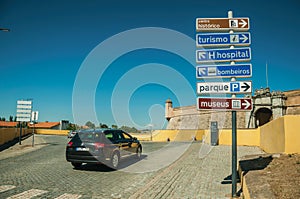 Car in street with signpost indicating public services and city attractions at Elvas