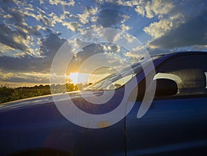 car at sunset, blue car in nature at sunset in the rays of the sun