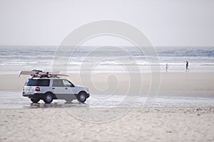 Car with surfboards on the Pacific coast beach