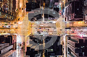 Car, taxi, and bus traffic on road intersection at night in Hong Kong downtown district, drone aerial top view. Asia city life