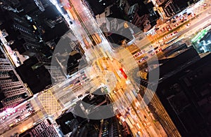 Car, taxi, and bus traffic on road intersection at night in Hong Kong downtown district, drone aerial top view. Asia city life