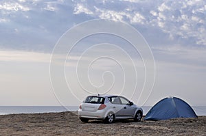 Car and a tent against the background of the sea.