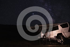 Car with tent or marquee with mountains silhouette and many stars background. Overlanding, car tourism concept. Adventure travel.