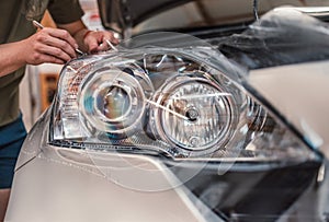 Car tinting service - Worker specialist apply tint foil on car headlight in workshop