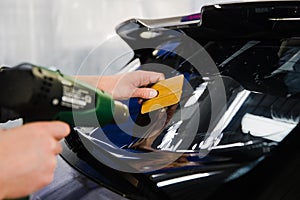 Car tinting. Worker applying tinting foil on car window