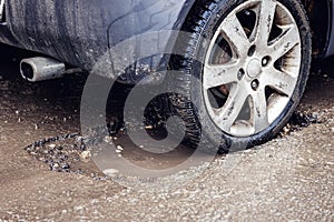 Car tire in big pothole on the road photo