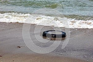 Car tire lying on sand on coastal beach