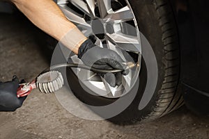 Car tire pressure check using air pressure guage. Mechanic inflating a car tire. Gas pumping of a car wheel. Car tire