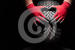 Car tire service and hands of mechanic holding new tyre on black background with copy space for text