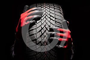 Car tire service and hands of mechanic holding new tyre on black background with copy space for text