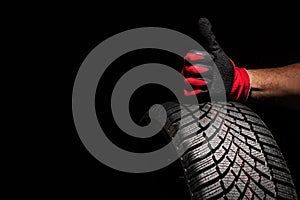 Car tire service and hands of mechanic holding new tyre on black background with copy space for text