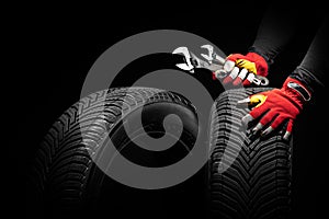 Car tire service and hands of mechanic holding new tyre and wrench on black background with copy space for text