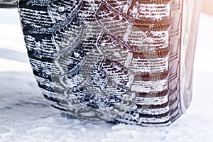 The car tire in the snow close up. Car tracks on the snow. Traces of the car in the snow. Winter tires. Tyres covered with snow at