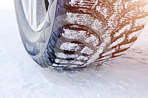 The car tire in the snow close up. Car tracks on the snow. Traces of the car in the snow. Winter tires. Tyres covered with snow at