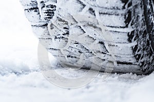 Car tire in the snow close up. Car tracks on the snow. Traces of the car in the snow. Winter tires. Tyres covered with snow at